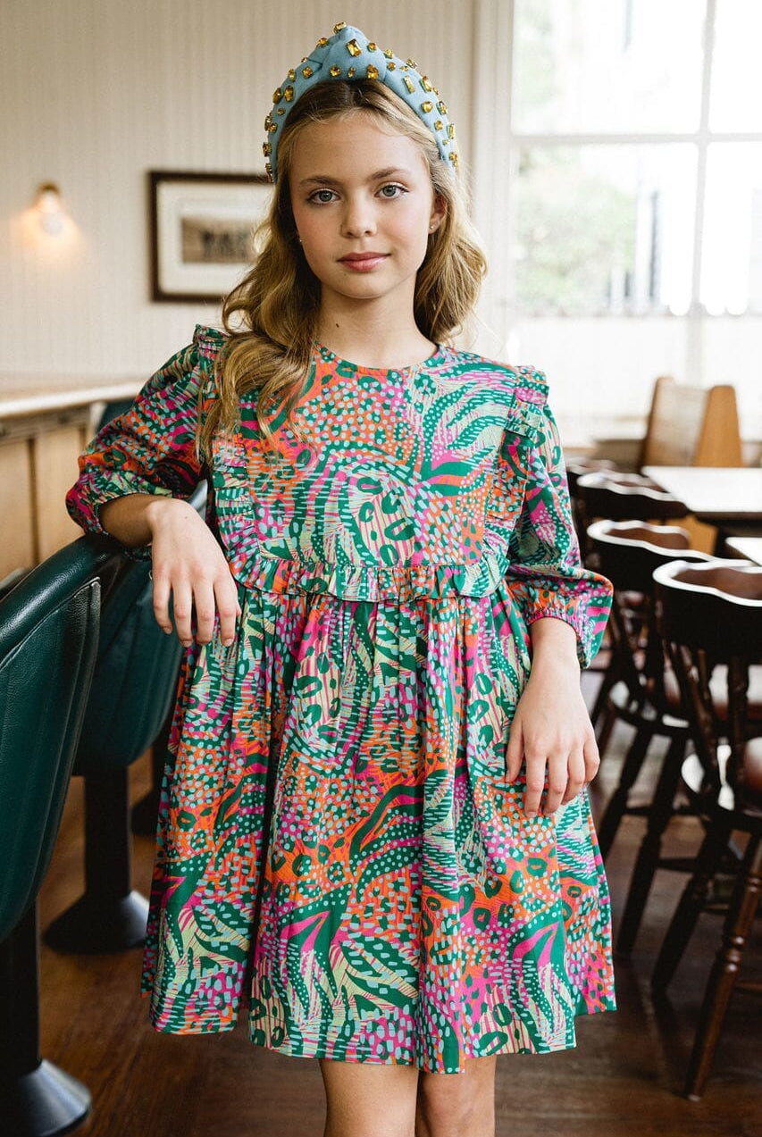 Girl smiling while wearing Willow Ruffle Bib dress.