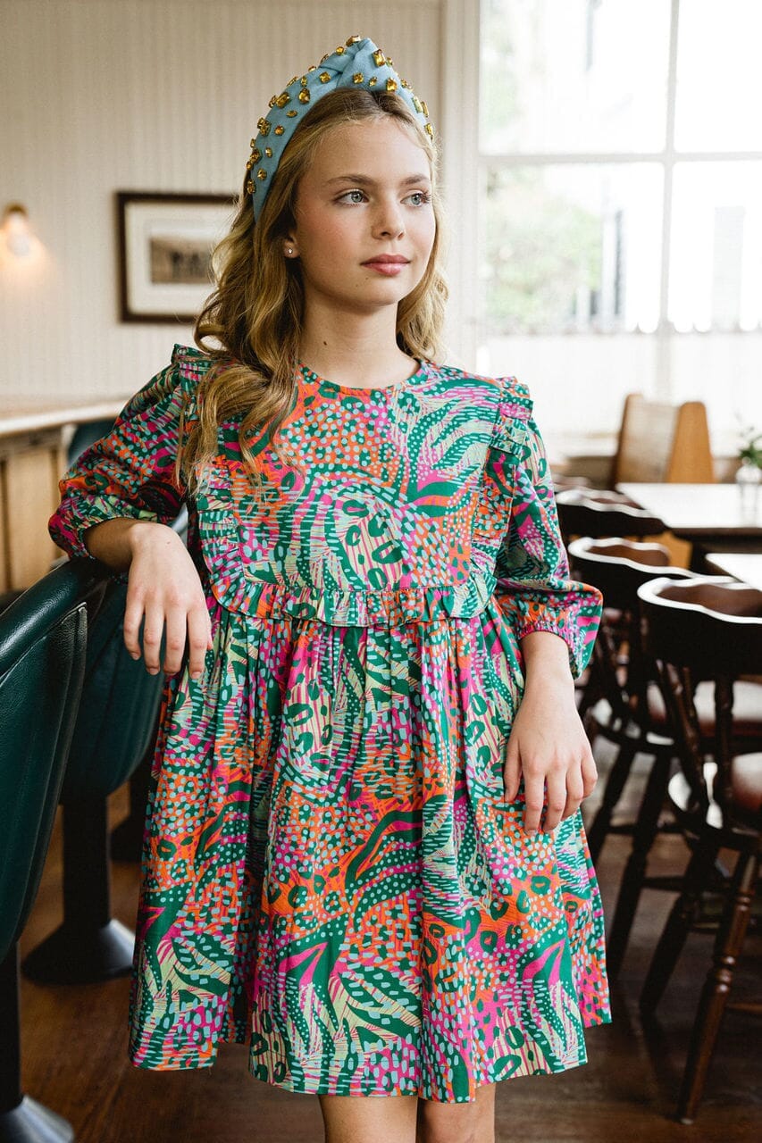Girl looking away while wearing Willow Ruffle Bib dress.