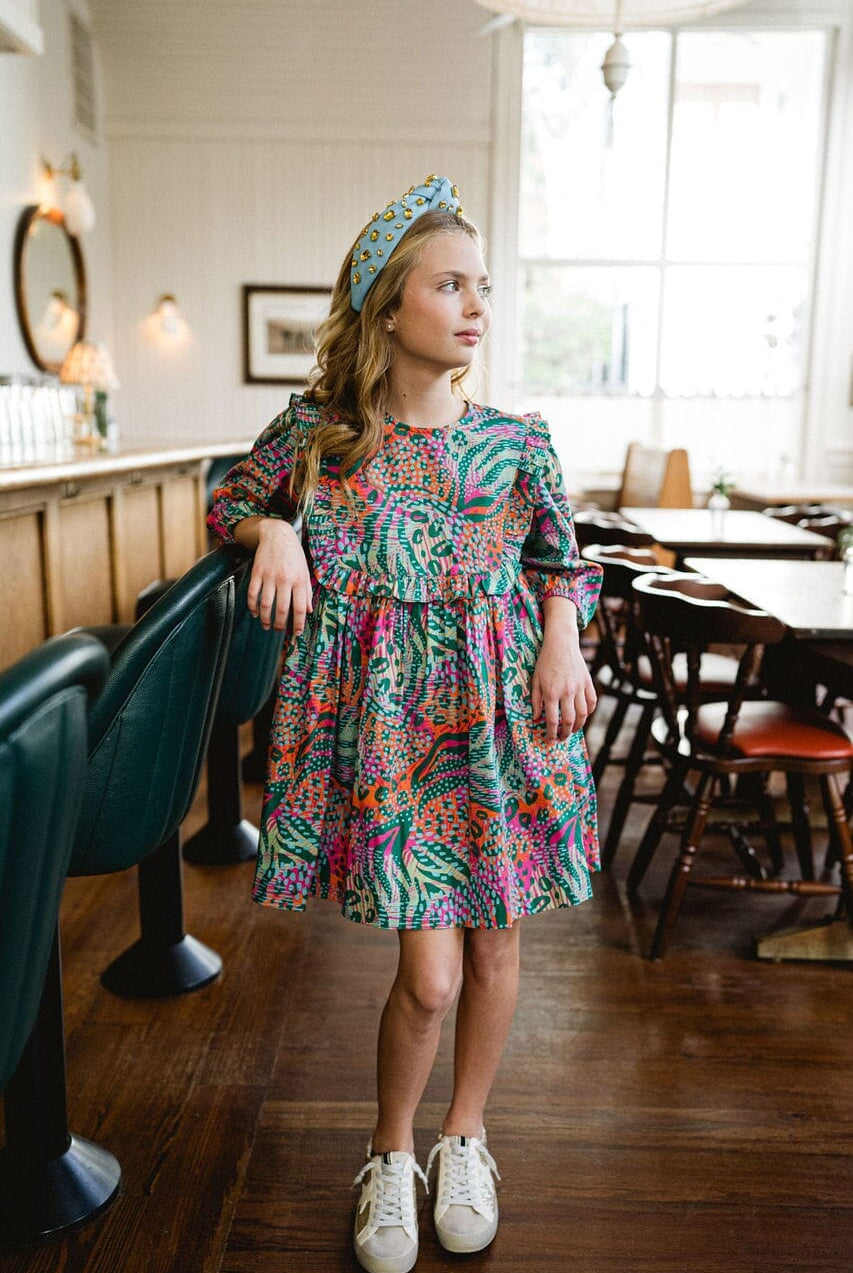 Girl looking away while wearing Willow Ruffle Bib dress.