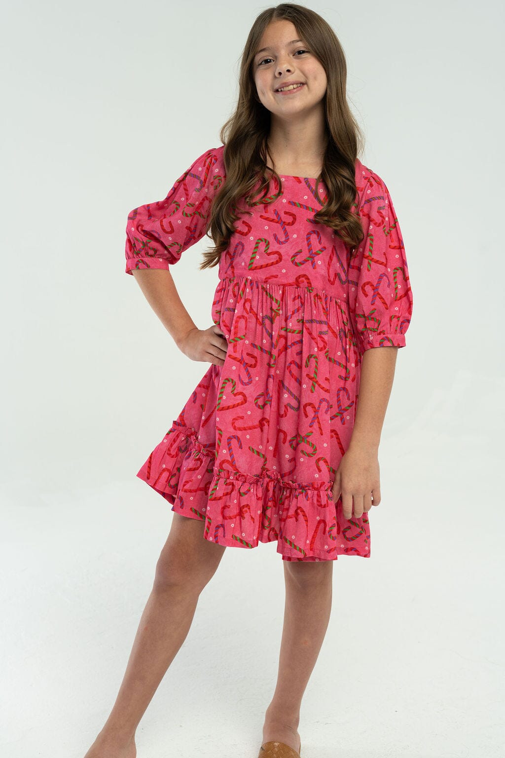 Girls Kenzie holiday dress in pink with festive candy cane and heart print, featuring puff sleeves and ruffle hem.