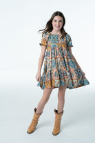 Girl wearing western cactus print dress with cowboy boots outdoors