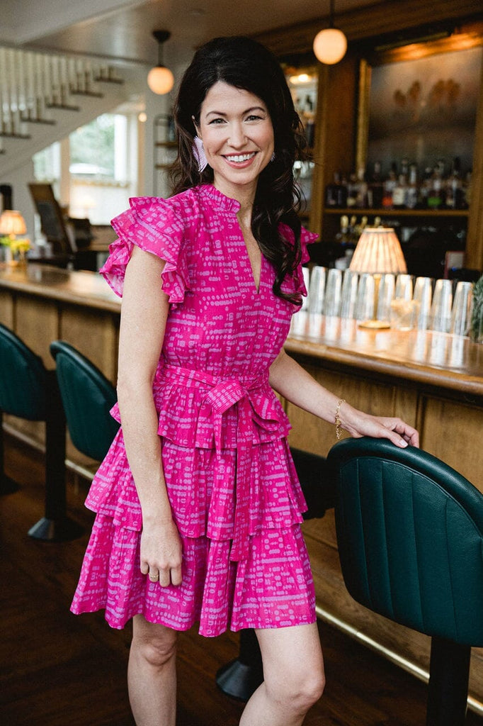 Woman smiling while wearing Delilah Ruffle Magenta dress.