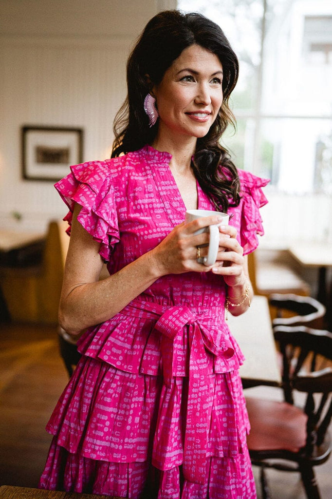 Woman smiling while wearing Delilah Ruffle Magenta dress.