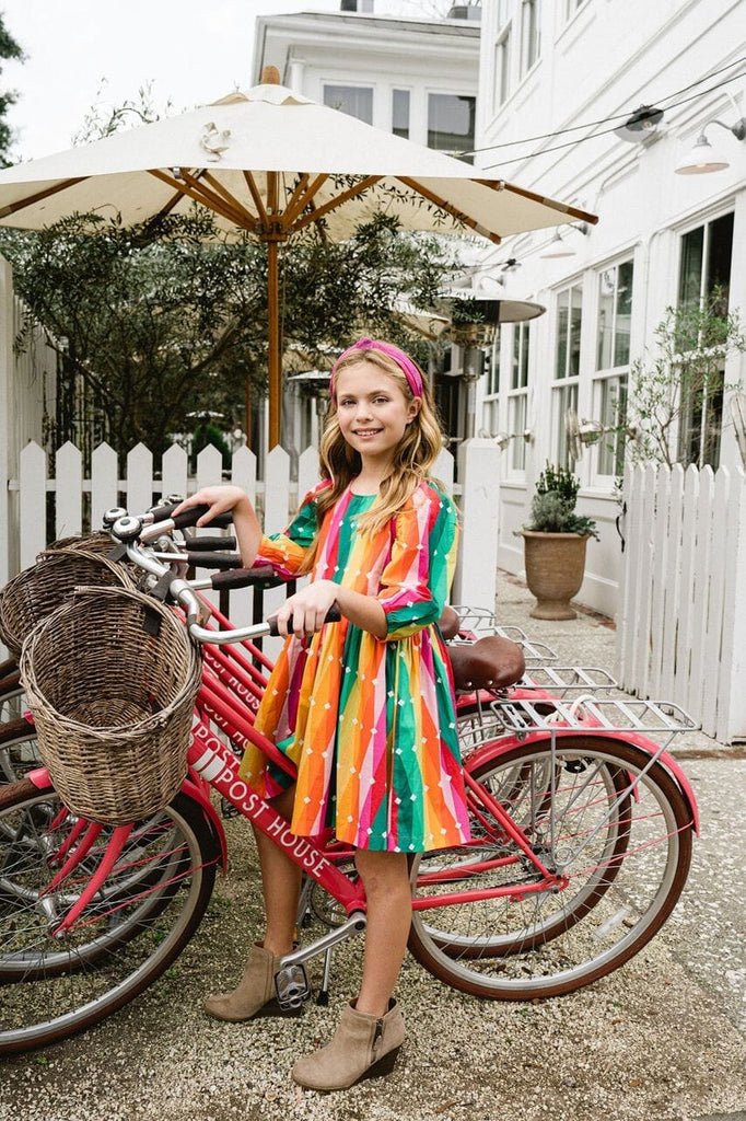 Girl on a bike while wearing Carnival dress.