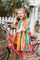 Girl on a bike while wearing Carnival dress.